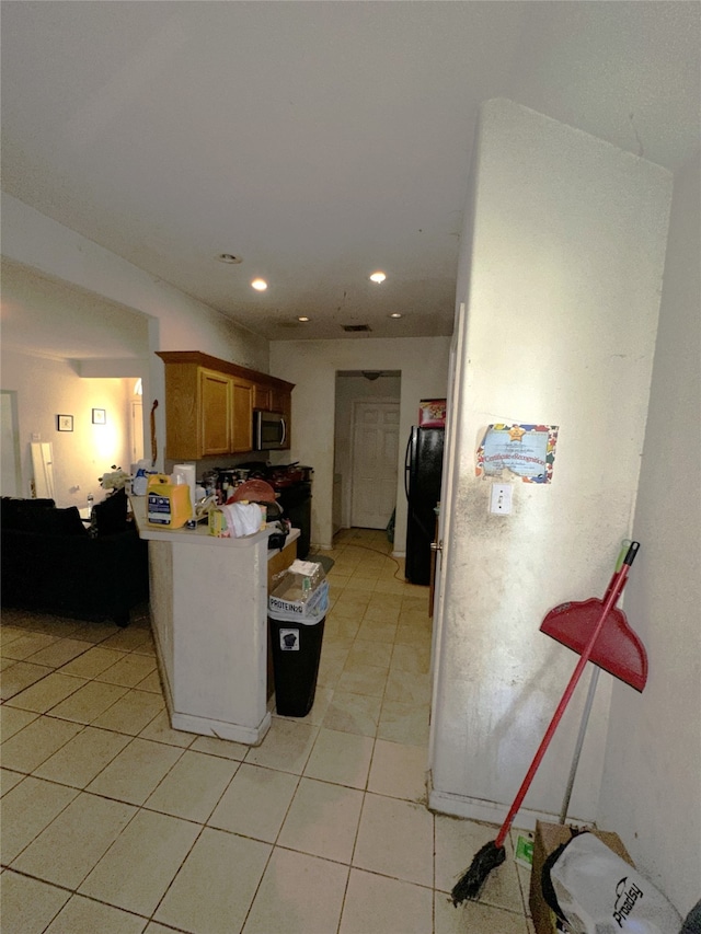 kitchen featuring black fridge and light tile patterned flooring