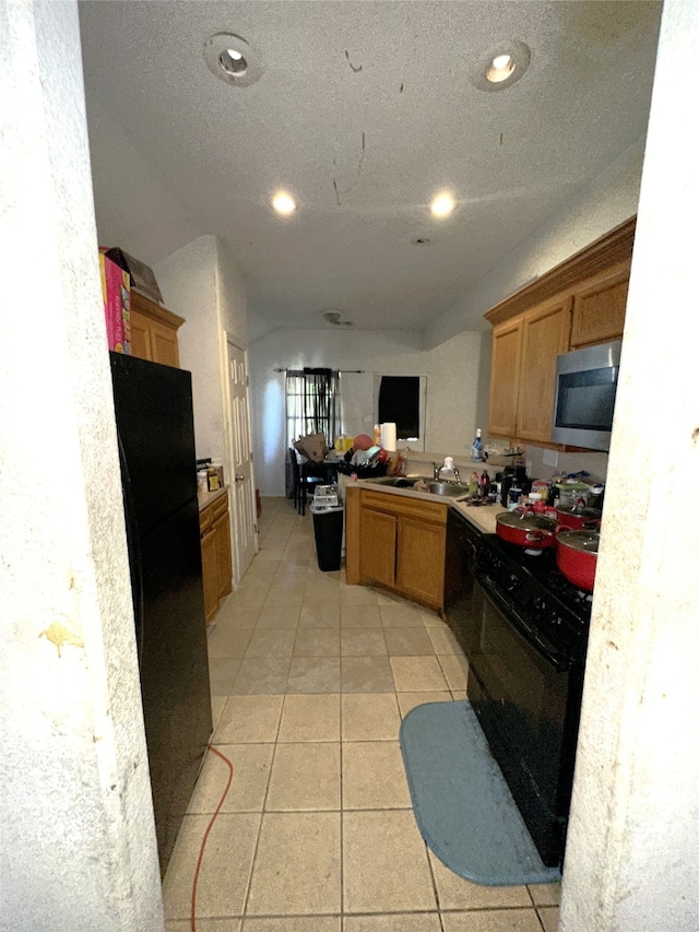 kitchen featuring sink, kitchen peninsula, a textured ceiling, light tile patterned floors, and black appliances