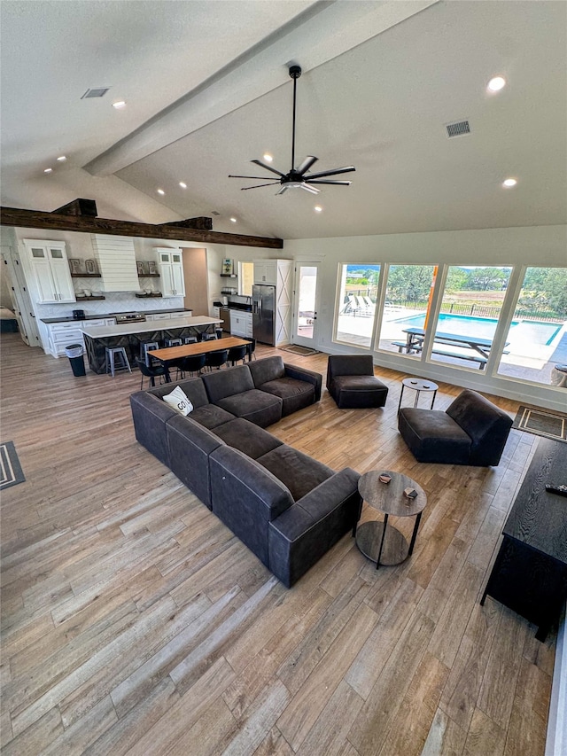 living room with vaulted ceiling with beams, a chandelier, and light hardwood / wood-style flooring