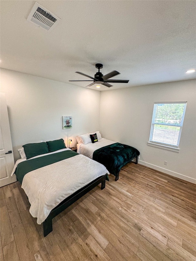 bedroom with ceiling fan, a textured ceiling, and light wood-type flooring