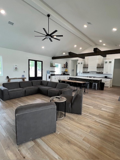 living room with vaulted ceiling with beams, ceiling fan, french doors, and light hardwood / wood-style floors