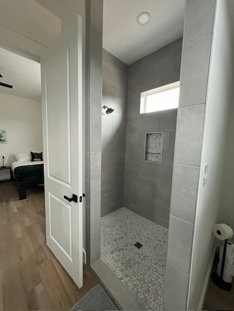 bathroom with a tile shower and wood-type flooring