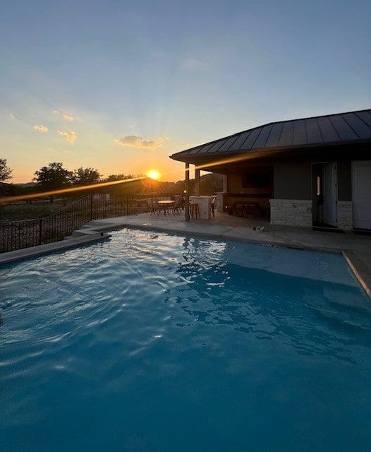 pool at dusk with a patio area