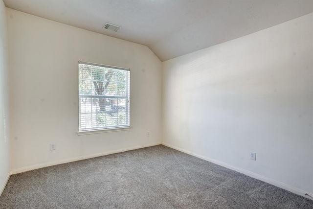 carpeted empty room featuring vaulted ceiling