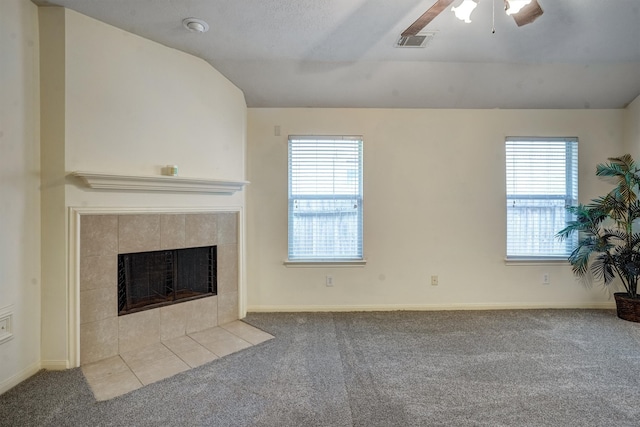 unfurnished living room with a healthy amount of sunlight, lofted ceiling, light carpet, and a tiled fireplace