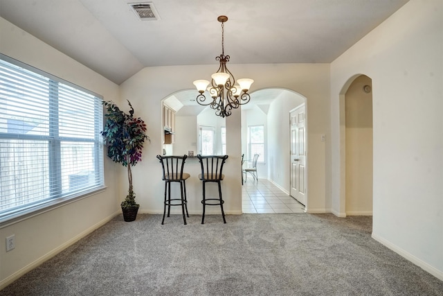 dining space with plenty of natural light, an inviting chandelier, light carpet, and vaulted ceiling