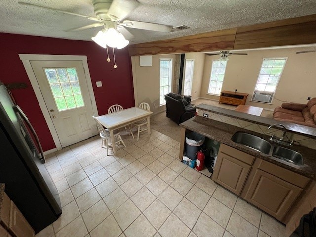 kitchen featuring a textured ceiling, ceiling fan, light tile patterned floors, and sink