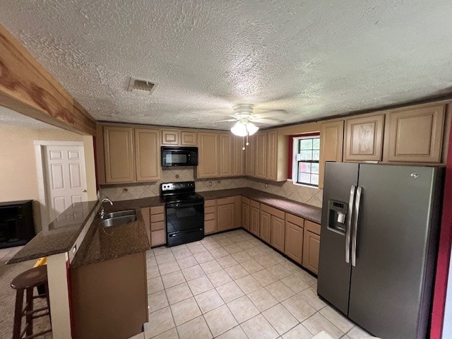 kitchen featuring sink, kitchen peninsula, a textured ceiling, a breakfast bar, and black appliances