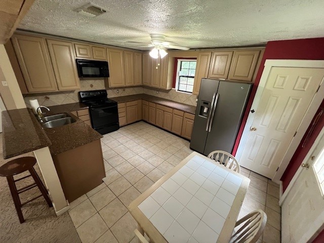 kitchen featuring black appliances, a kitchen breakfast bar, sink, ceiling fan, and light tile patterned floors