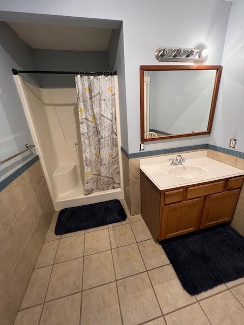 bathroom featuring tile patterned flooring, vanity, tile walls, and curtained shower