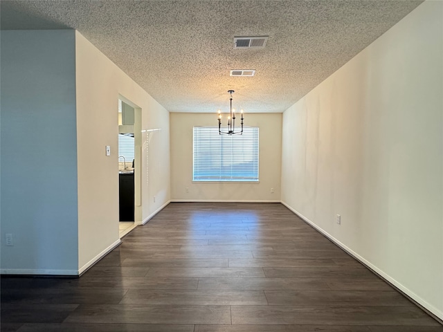 unfurnished dining area featuring a textured ceiling, dark hardwood / wood-style flooring, an inviting chandelier, and sink