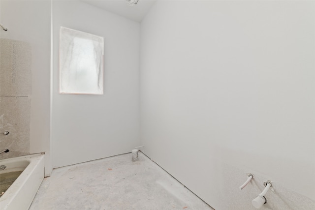 bathroom with concrete flooring and a tub to relax in