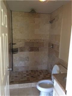 bathroom with tiled shower, vanity, and toilet