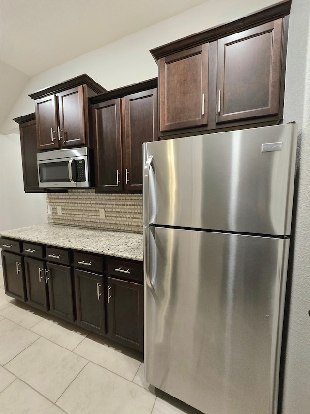 kitchen featuring dark brown cabinets, backsplash, stainless steel appliances, and light tile patterned flooring