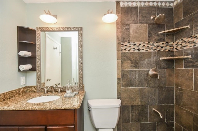 bathroom featuring vanity, toilet, and tiled shower