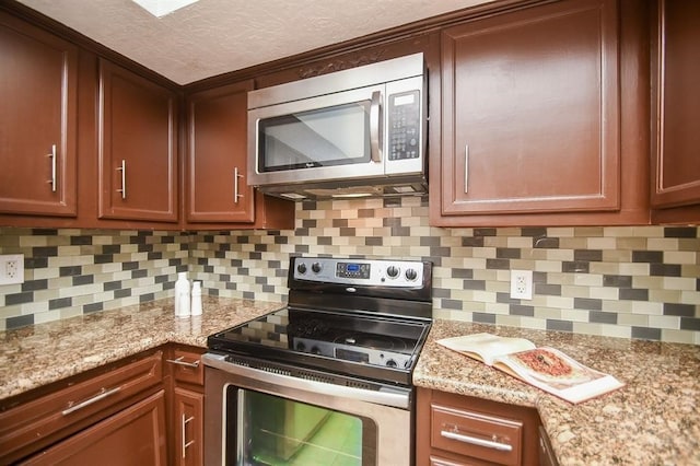 kitchen with backsplash, light stone counters, and stainless steel appliances