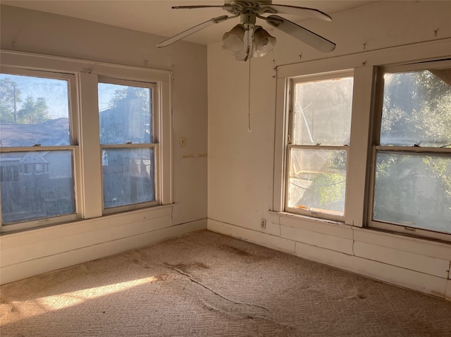 empty room with plenty of natural light, ceiling fan, and carpet floors