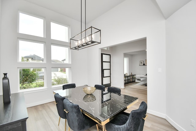 dining room featuring light hardwood / wood-style flooring and a high ceiling