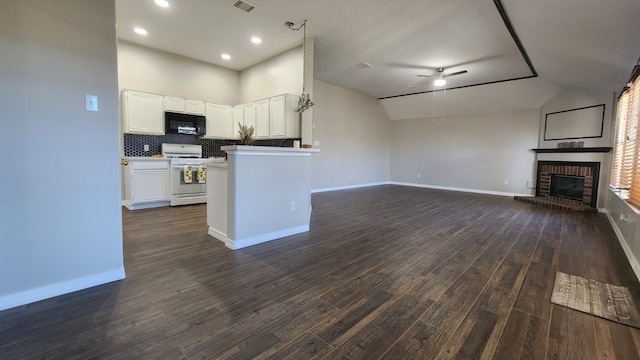 kitchen with white cabinetry, dark hardwood / wood-style floors, vaulted ceiling, a fireplace, and white stove