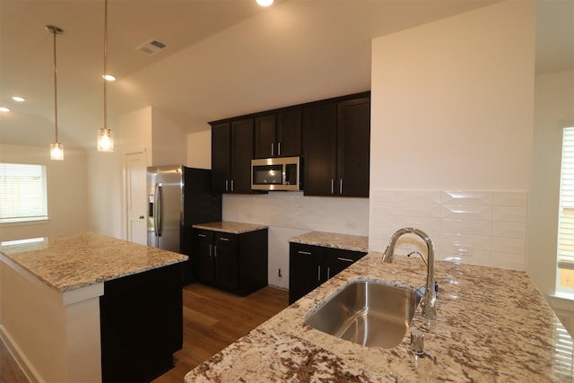 kitchen with decorative light fixtures, light stone countertops, appliances with stainless steel finishes, and sink