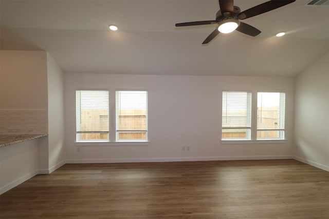 spare room featuring lofted ceiling, ceiling fan, a healthy amount of sunlight, and dark wood-type flooring