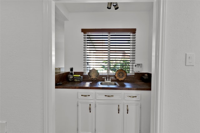 bar featuring sink and white cabinets