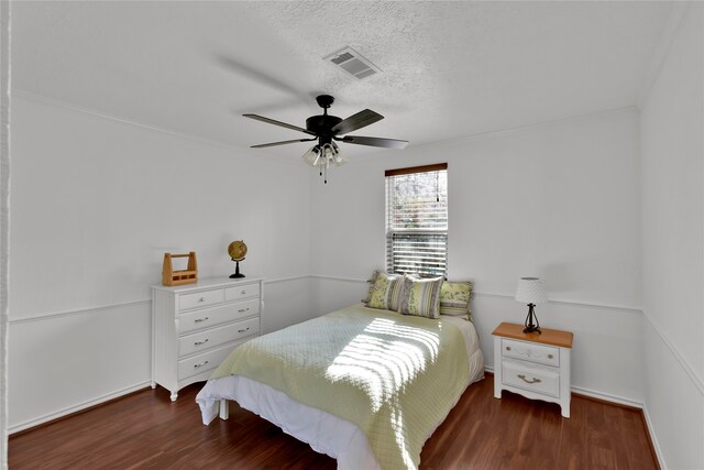 bedroom with a textured ceiling, ceiling fan, and dark wood-type flooring