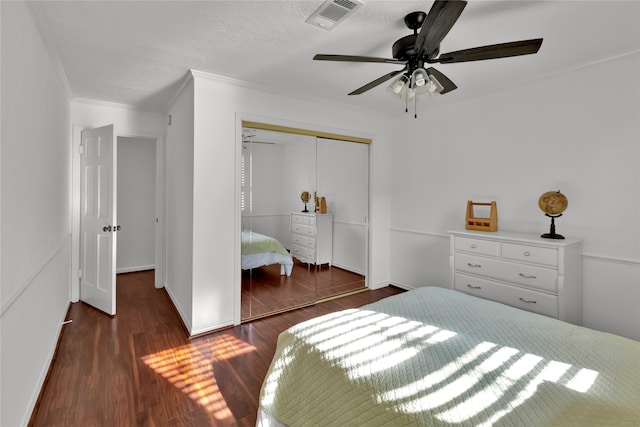 bedroom featuring a textured ceiling, ceiling fan, crown molding, dark wood-type flooring, and a closet