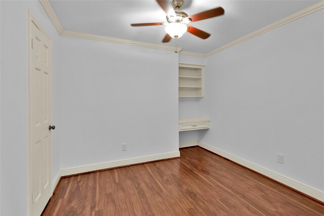 unfurnished bedroom with built in desk, hardwood / wood-style flooring, ceiling fan, and crown molding