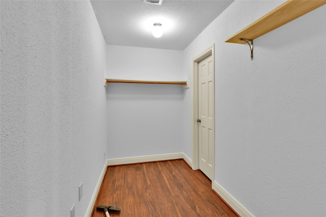 walk in closet with dark wood-type flooring