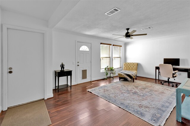 entrance foyer with ceiling fan, crown molding, dark wood-type flooring, and a textured ceiling