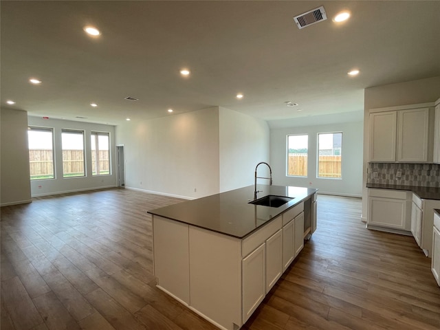 kitchen with white cabinets, sink, an island with sink, and a healthy amount of sunlight