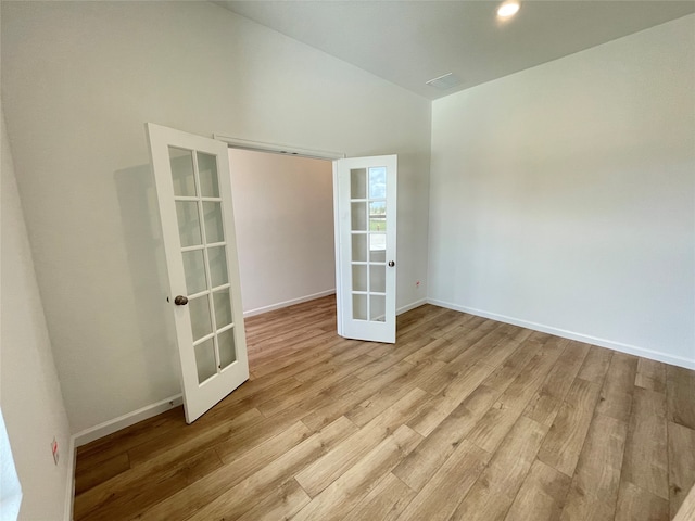 unfurnished room with french doors, vaulted ceiling, and light hardwood / wood-style flooring