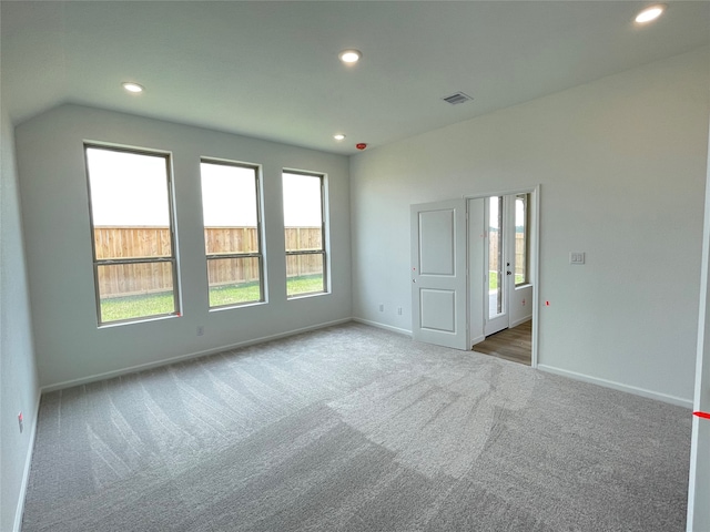 carpeted empty room featuring lofted ceiling