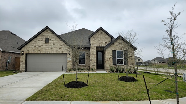 french country inspired facade with a front yard, an attached garage, brick siding, and driveway