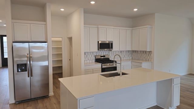 kitchen featuring a sink, decorative backsplash, appliances with stainless steel finishes, and light wood-style flooring