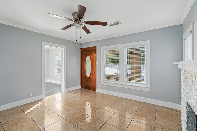 entrance foyer featuring a brick fireplace, plenty of natural light, crown molding, and ceiling fan