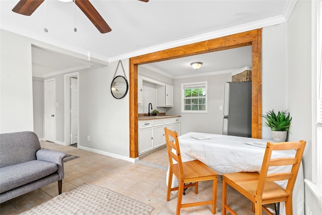 dining space with ceiling fan, sink, light tile patterned flooring, and ornamental molding