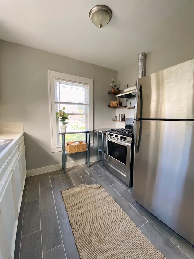 kitchen featuring white cabinetry, stainless steel appliances, and exhaust hood