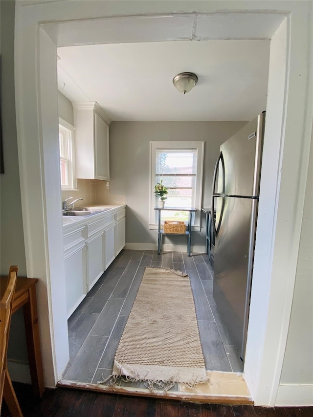 kitchen featuring white cabinets, dark hardwood / wood-style floors, stainless steel refrigerator, and sink