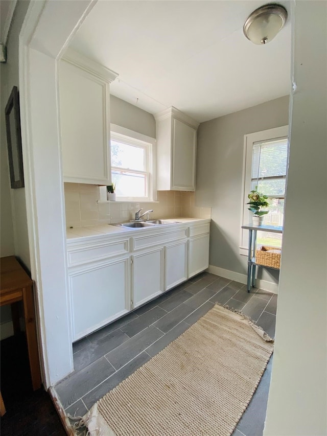 kitchen with tasteful backsplash, sink, and white cabinets