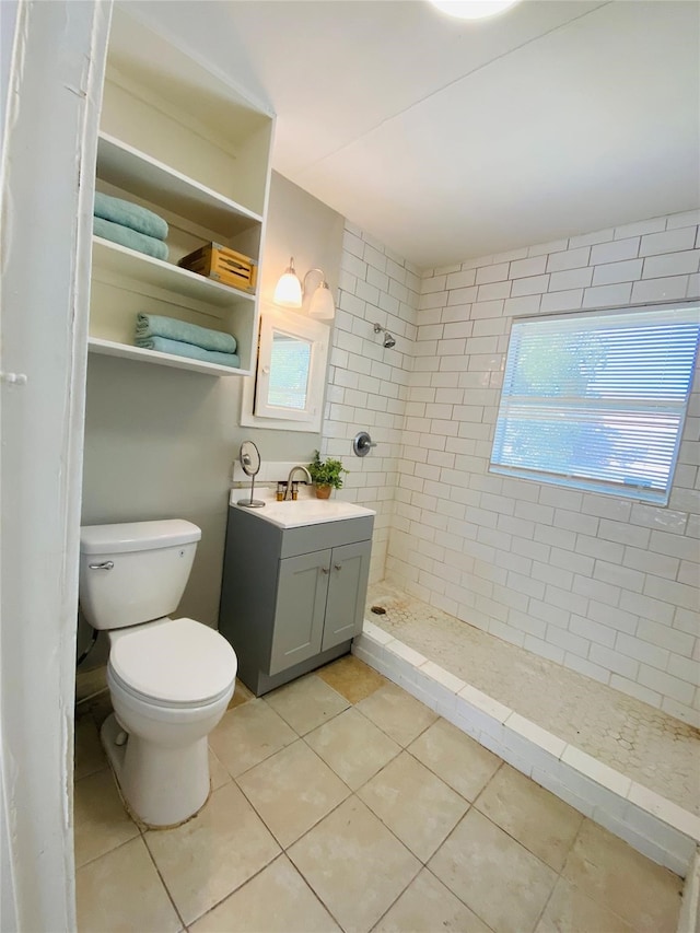 bathroom with toilet, tile patterned flooring, vanity, and tiled shower