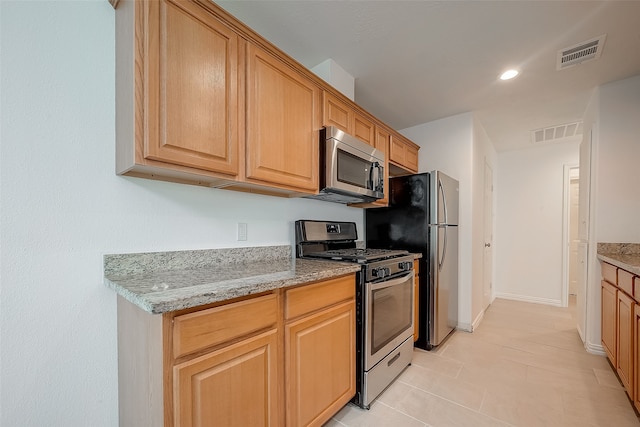 kitchen with light stone counters, light tile patterned floors, and stainless steel appliances