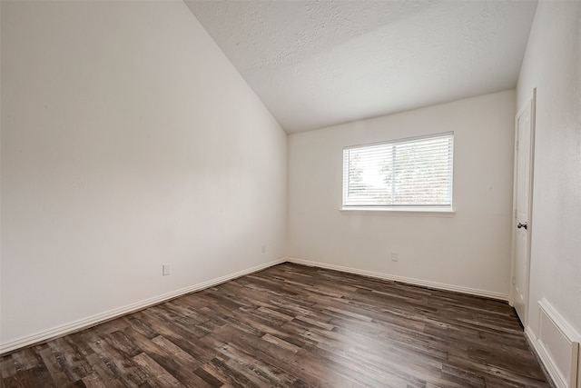 spare room with a textured ceiling, dark hardwood / wood-style flooring, and lofted ceiling