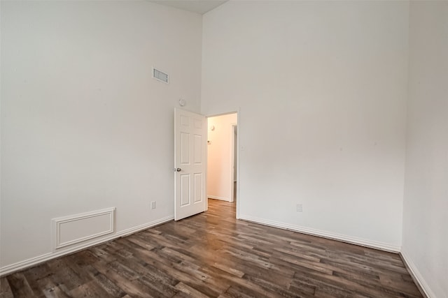 spare room featuring a high ceiling and dark hardwood / wood-style floors