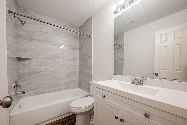 full bathroom featuring vanity, a textured ceiling, hardwood / wood-style floors, toilet, and tiled shower / bath