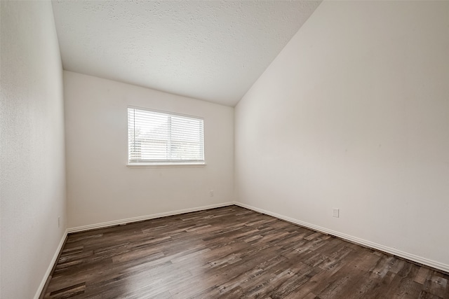 empty room with dark hardwood / wood-style floors, lofted ceiling, and a textured ceiling