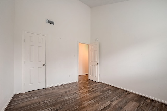 spare room with a towering ceiling and dark hardwood / wood-style floors