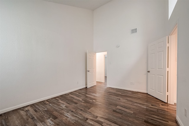 empty room featuring dark hardwood / wood-style floors and a towering ceiling