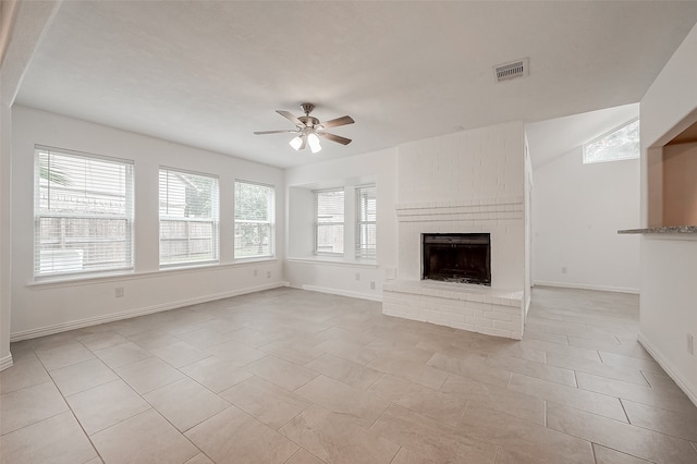 unfurnished living room with a wealth of natural light, a fireplace, ceiling fan, and light tile patterned floors